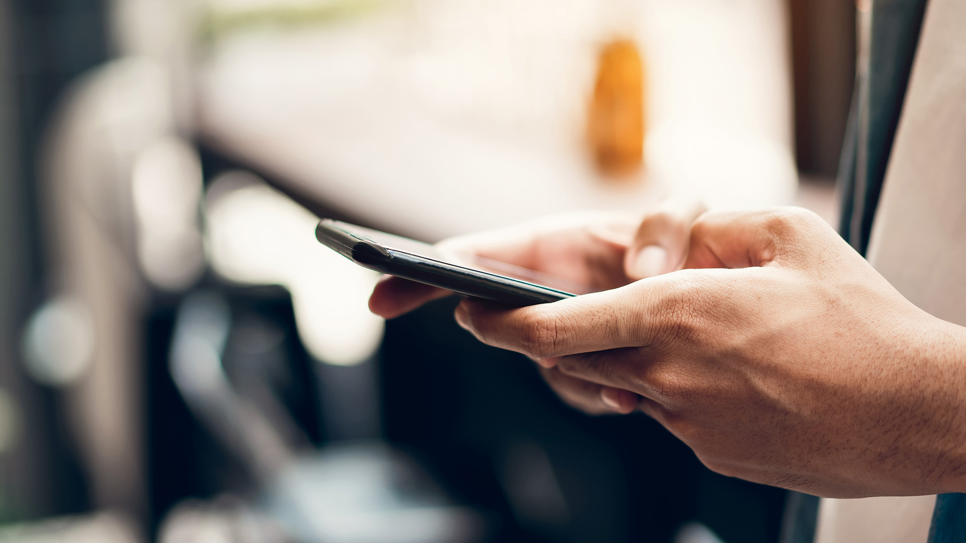 The image shows a person using a smartphone, with the device held in their hands.