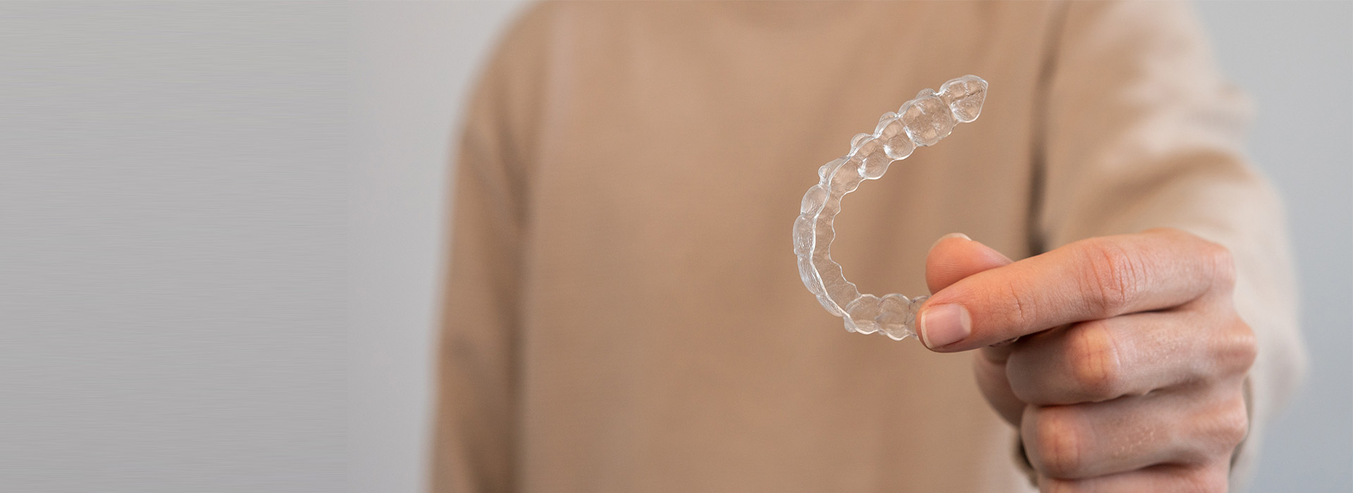 The image shows a person holding a soap bubble with their hand, against a neutral background.