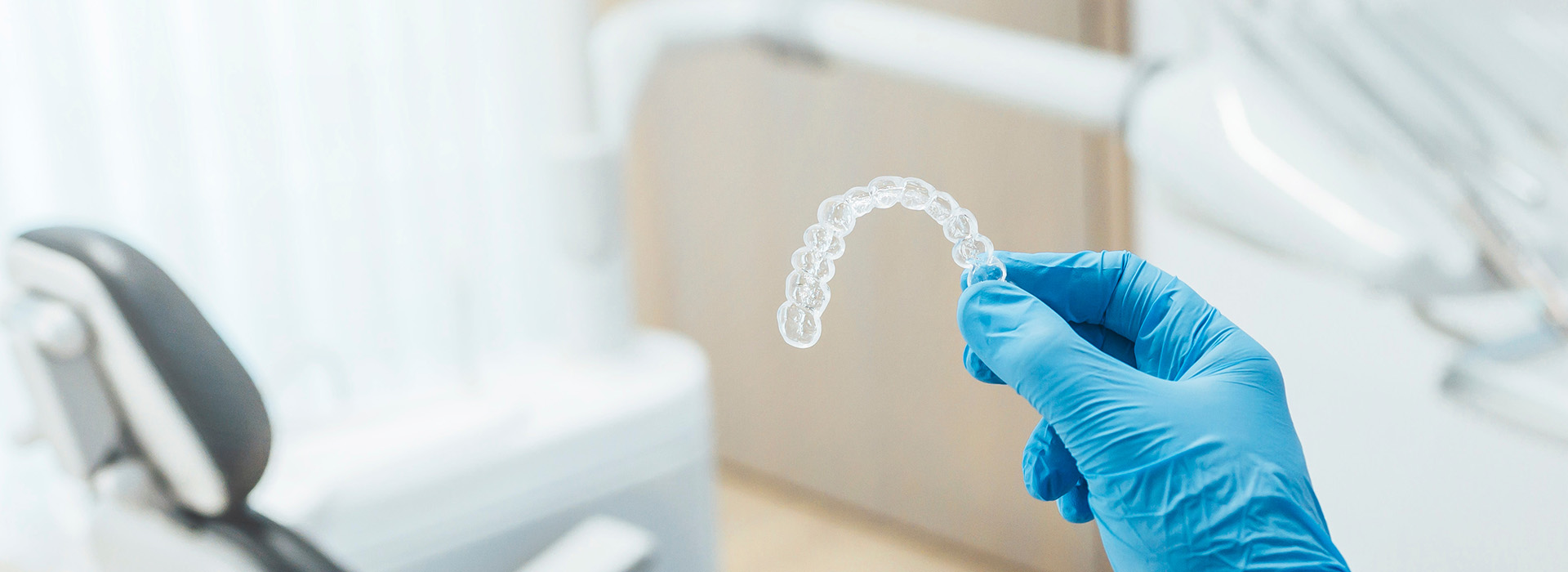 The image shows a close-up of a transparent dental impression material on a dental tray, with a blurred background that includes what appears to be a medical or dental setting.