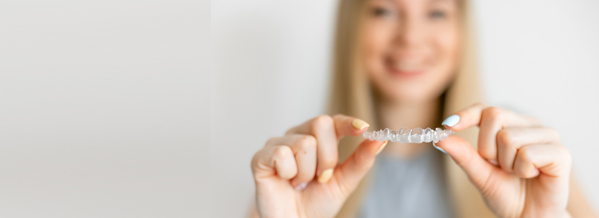 A woman holds a small, shiny object in her hand against a blurred background.