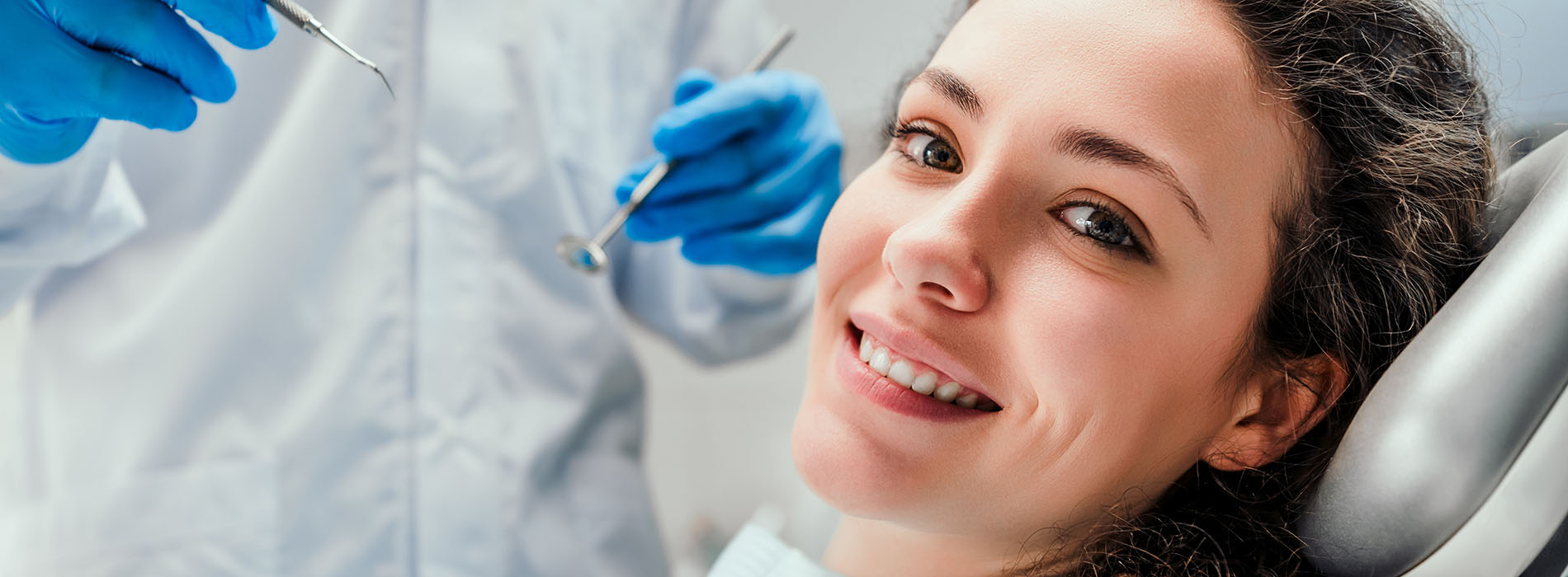 A woman sitting in a dental chair, receiving dental care from a professional.