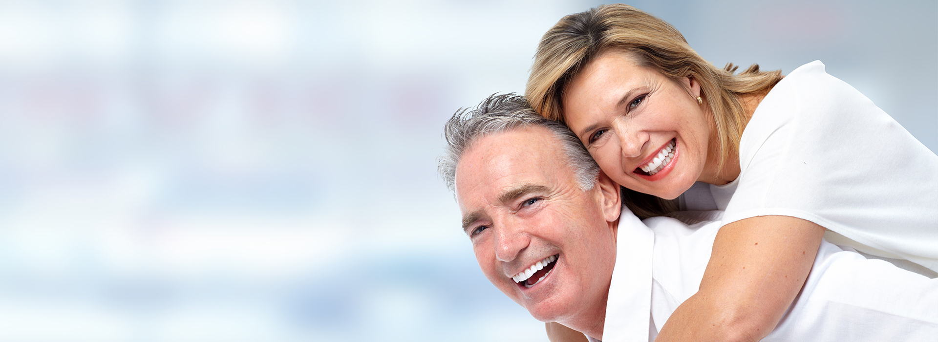 An elderly couple smiling and embracing each other.