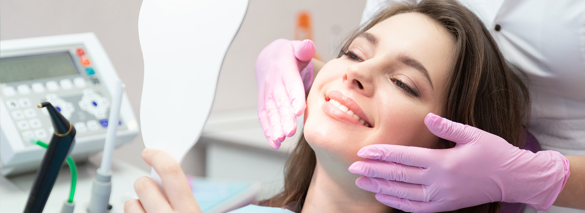 A woman receiving dental care with a dental hygienist using a device to clean her teeth.