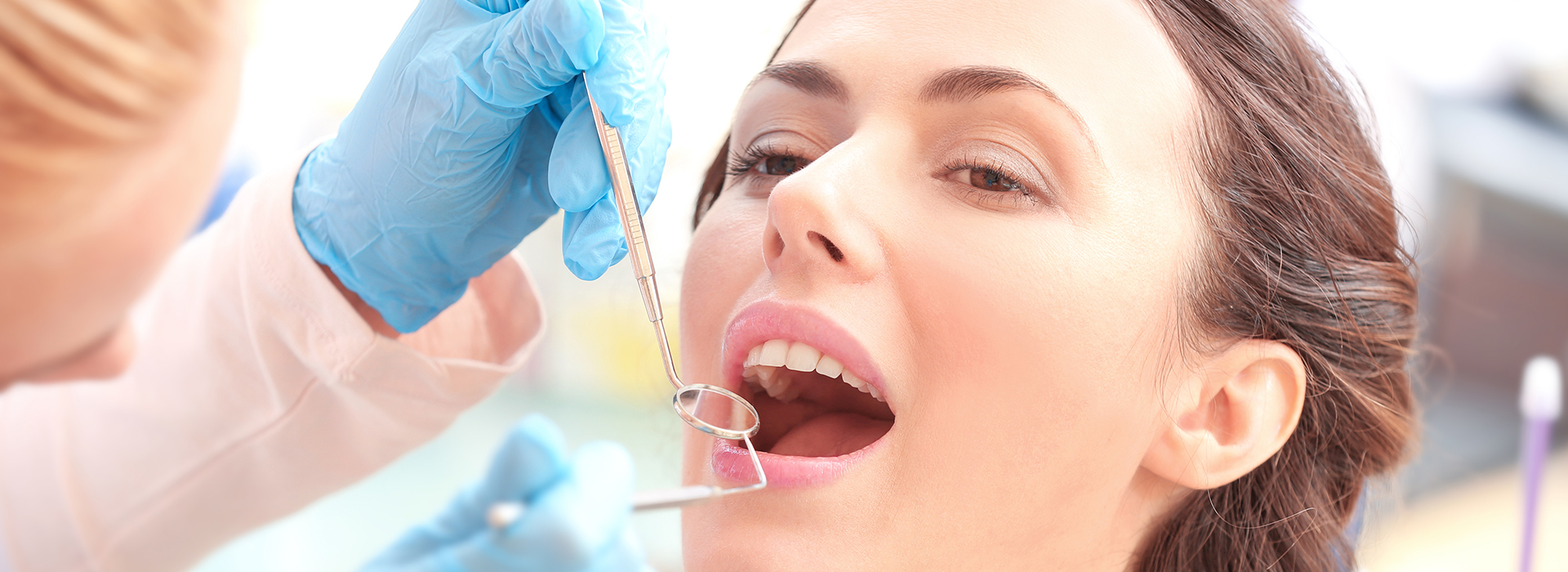 A woman receiving dental care with a dentist performing the procedure.