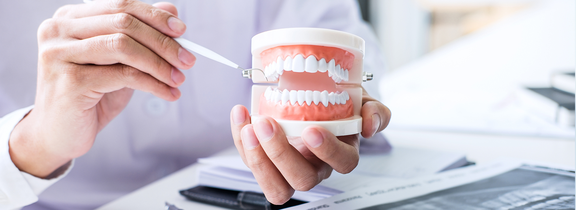 The image depicts a person holding a mug with a tooth model inside, suggesting a dental or oral health context.