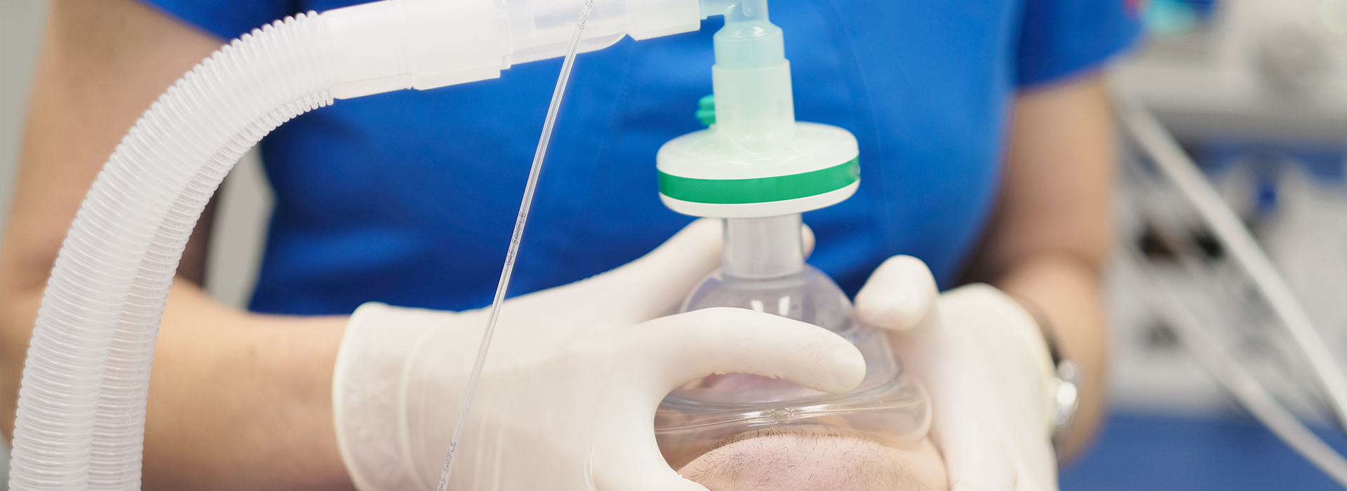 A person wearing gloves is handling a clear plastic bag with a green cap, containing a white substance, possibly in a laboratory setting.