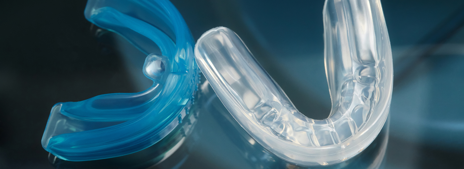 The image features a blue and clear plastic toothbrush head with bristles, set against a dark background.