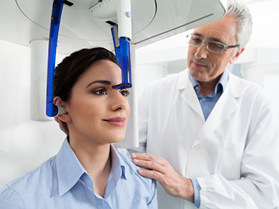 The image depicts a medical setting where a woman is receiving a dental or orthodontic examination, with a dentist using advanced technology to inspect her teeth and oral health.