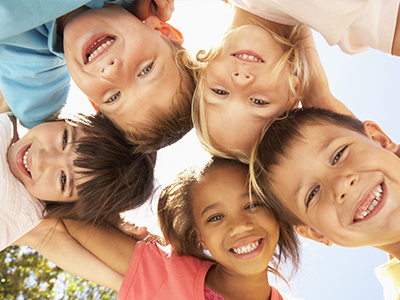 A group of children with diverse expressions, smiling and looking directly at the camera.